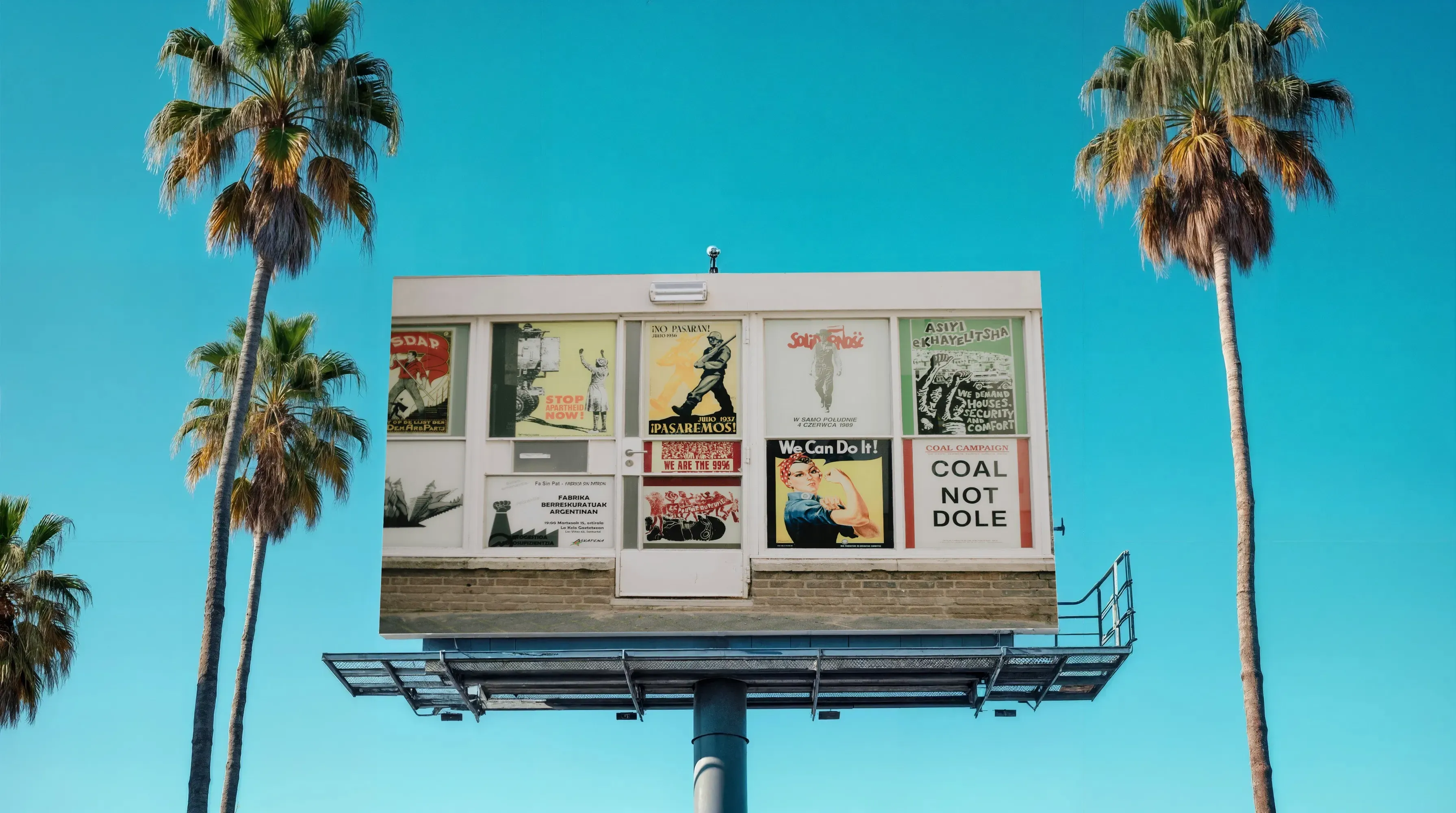 Billboard mockup with palm trees and vintage protest posters against a clear blue sky.
